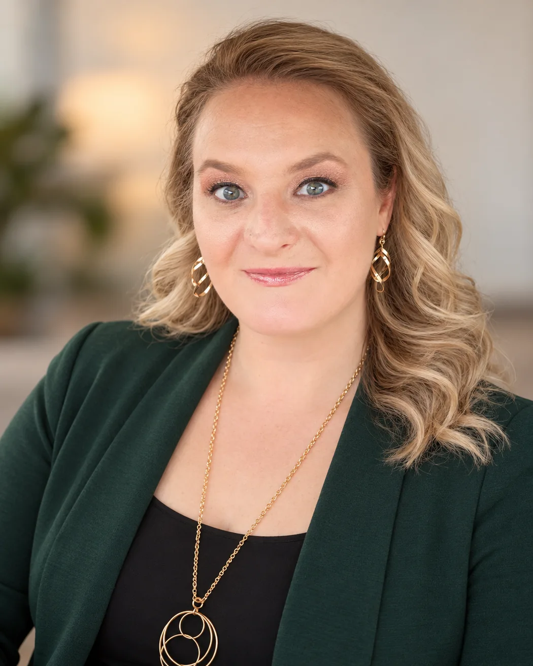Professional headshot of Kasey Mussared in a forest-green blazer